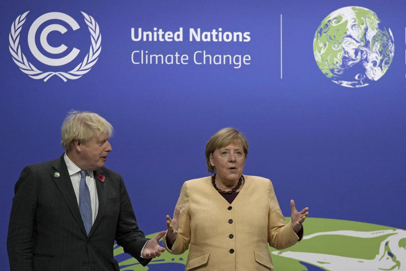 British Prime Minister Boris Johnson, left, greets German Chancellor Angela Merkel as she arrives at the COP26 U.N. Climate Summit in Glasgow, Scotland, on Nov. 1, 2021. Merkel has been credited with raising Germany’s profile and influence, helping hold a fractious European Union together, managing a string of crises and being a role model for women in a near-record tenure. Her designated successor, Olaf Scholz, is expected to take office on December 8, 2021. (AP File Photo)